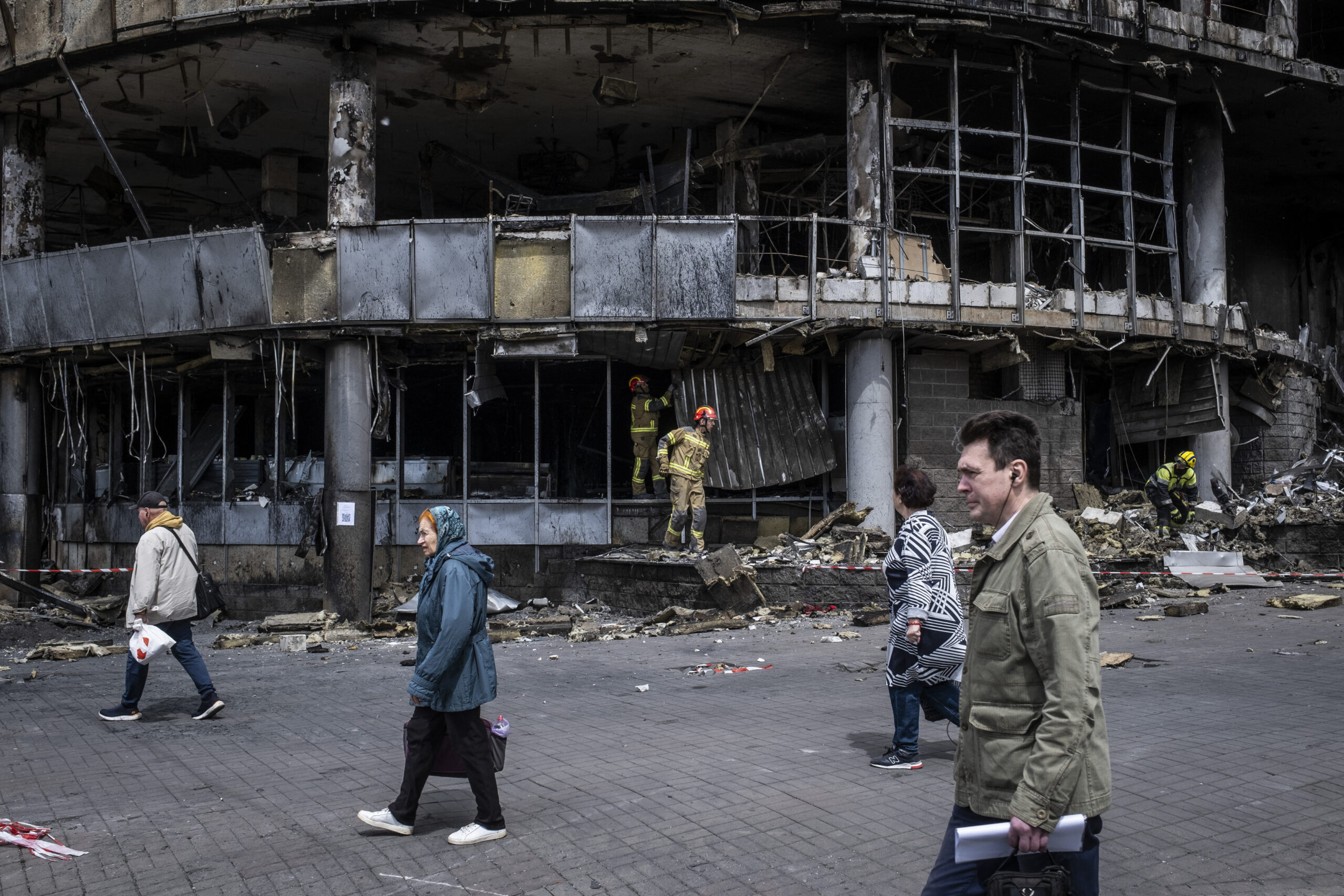People are walking in front of a destroyed shopping mall in Liukanivka district in Kyiv.
