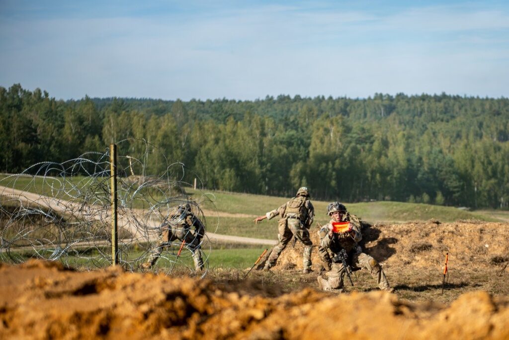 A US Army paratroopers assigned to 54th Brigade Engineer Battalion use a VS-17 panel to signal that the breach is clear for a maneuver element to move forward during a combined arms live fire exercise.