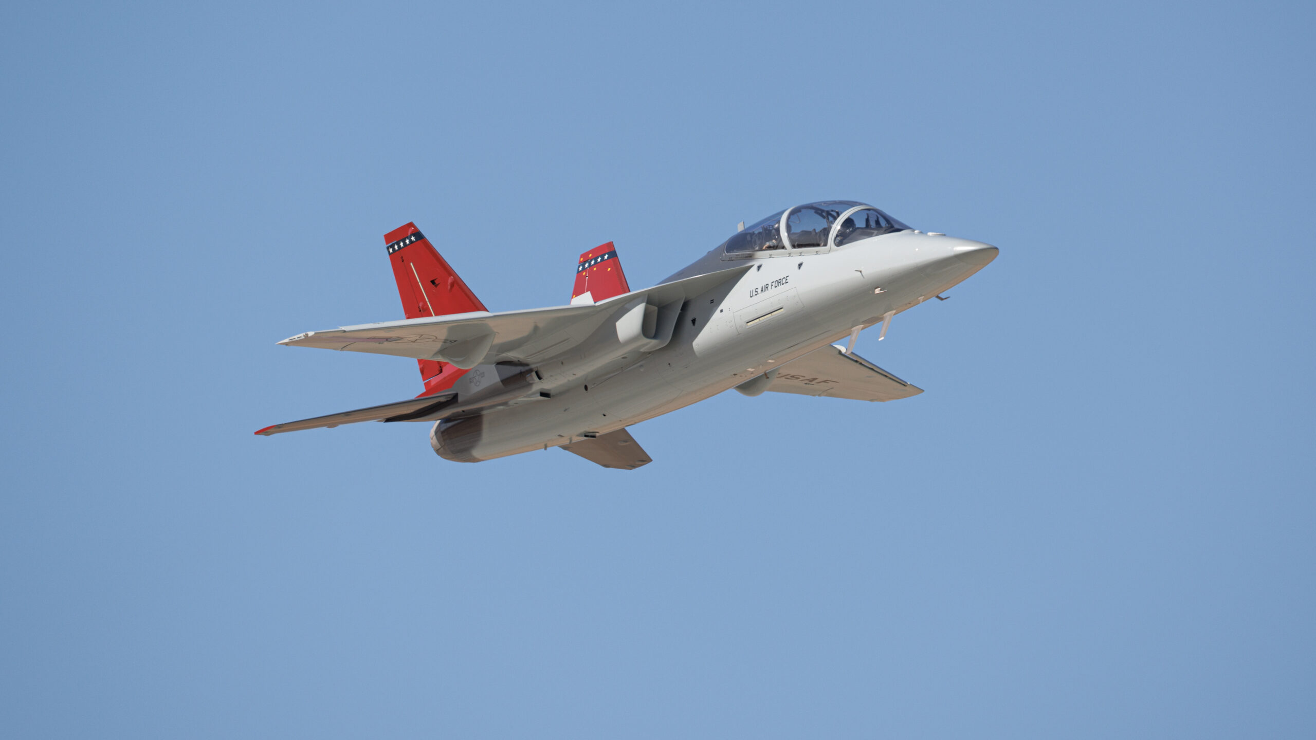 The first T-7A Red Hawk, piloted by USAF test pilot Maj. Jonathan “Gremlin” Aronoff and Boeing test pilot Steve “Bull” Schmidt, soars over Edwards Air Force Base, California, Nov. 8, prior to arrival. The T-7A will replace the 1960s-era T-38 aircraft by providing advanced pilot training capabilities for aviators learning to fly both tactical and bomber aircraft.